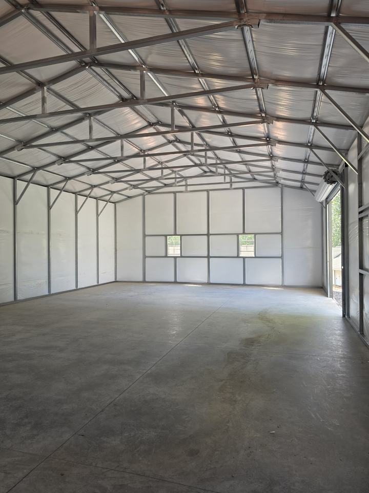 Interior of the finished building with a smooth concrete floor and steel truss framing