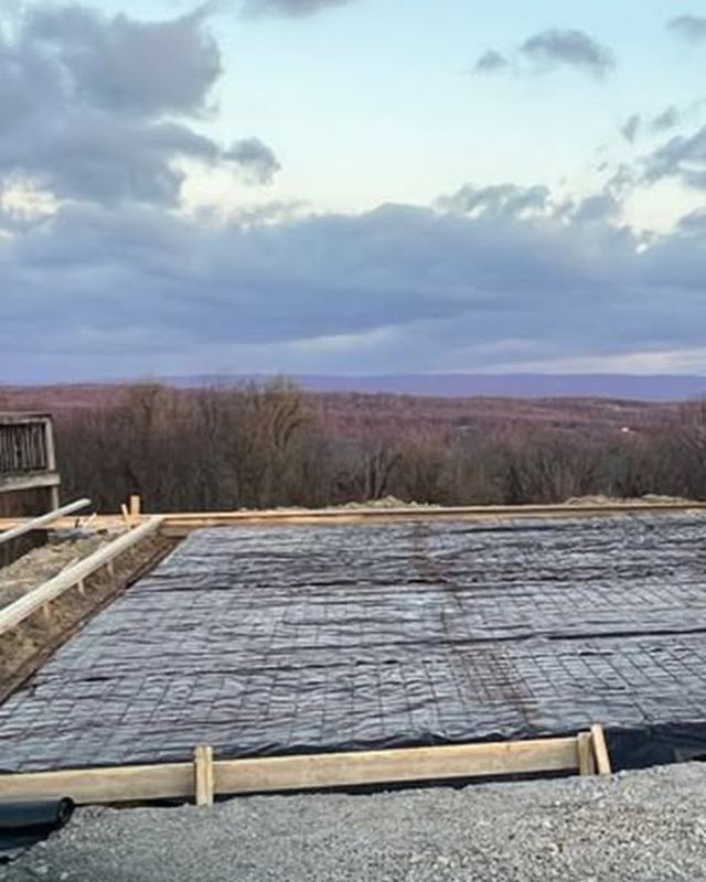 Wood forms set around the pad with black vapor barrier and wire mesh laid inside, overlooking a valley