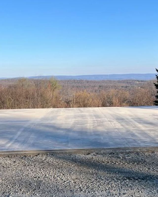 Finished concrete slab on a gravel pad with a mountain view behind it